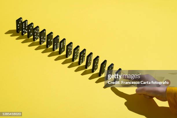 hand pointing at a row of dominoes - dominoes stock pictures, royalty-free photos & images