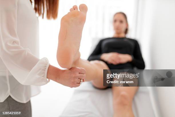 患者の足をまっすぐに拳で持つ理学療法士 - sole ストックフォトと画像