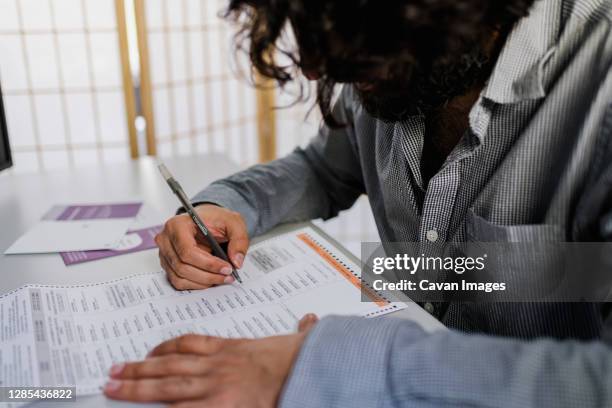 unrecognizable man completing absentee ballot 2020 election - absentee ballot fotografías e imágenes de stock