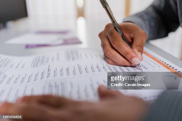 close up of hands man's completing absentee ballot - indian vote stock pictures, royalty-free photos & images