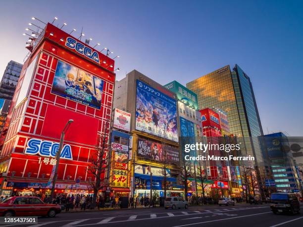 akihabara, tokyo, garish signboards and buildings illuminated brightly at dusk - akihabara stock pictures, royalty-free photos & images