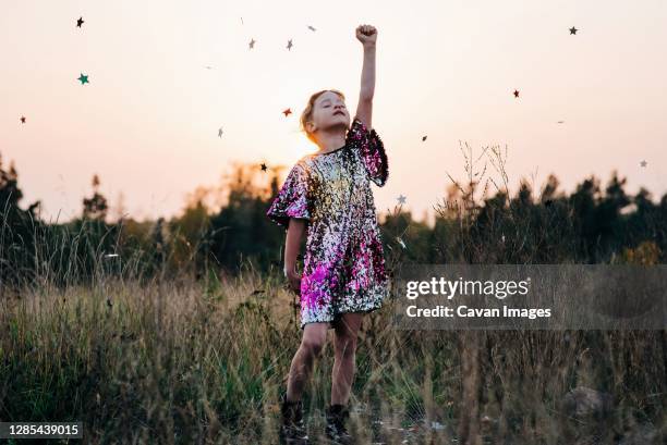 girl standing strong in a sparkly dress with star confetti falling - glitter hair stock-fotos und bilder