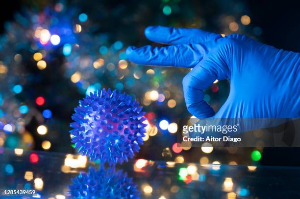 concept of elimination of the pandemic caused by the coronavirus: a scientist is going to give a coronavirus strongly with his finger to eliminate it from the earth. colorful christmas lights in the background. interpretation with humor of the pandemic. - punt kick stock pictures, royalty-free photos & images