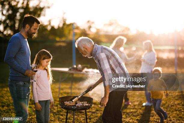 extended family having barbecue time in the front yard. - backyard grilling stock pictures, royalty-free photos & images