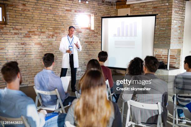 male doctor talking to group of people on presentation in the hospital. - doctor presentation stock pictures, royalty-free photos & images