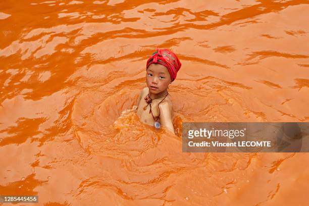 Une fillette de la communauté Tamang portant un turban rouge et un pendentif à l'effigie du Dalaï Lama se baigne dans les sources thermales, 21 avril...