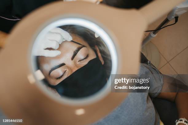 professional makeup artist paints eyebrows to client - tatuagem de henna imagens e fotografias de stock