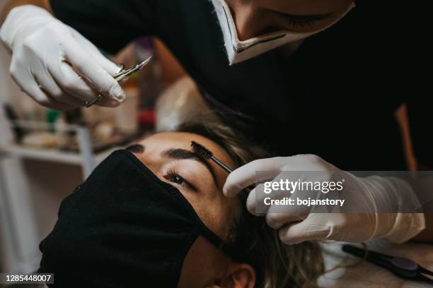 makeup artist combs eyebrows of young woman with a brush - brow lamination stock pictures, royalty-free photos & images