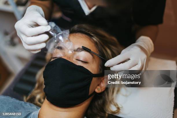 makeup artist combs eyebrows of young woman with a brush - brow lamination stock pictures, royalty-free photos & images