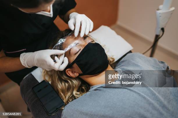 permanent make-up für augenbrauen im schönheitssalon - brow lamination stock-fotos und bilder