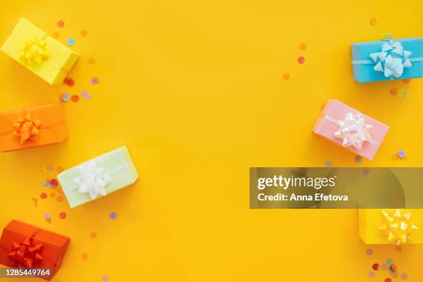 colorful gift boxes with ribbons on yellow background - birthday background stock pictures, royalty-free photos & images