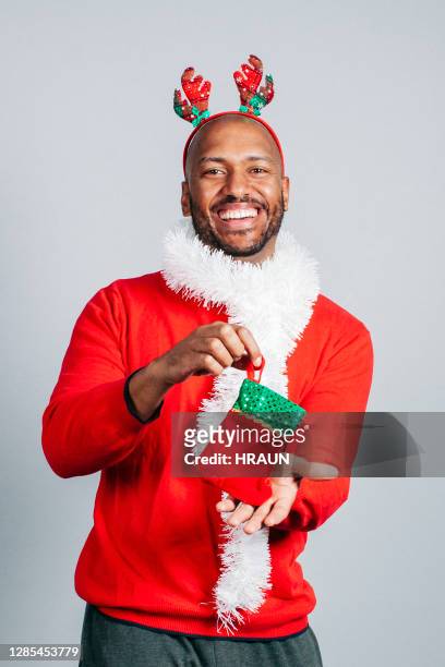 cheerful man holding christmas stockings - santa hat stock pictures, royalty-free photos & images