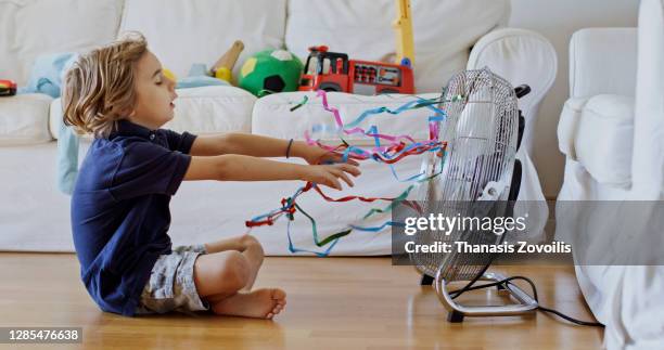 five year old boy standing in front of a fan and enjoy cool waves - electric fan stockfoto's en -beelden