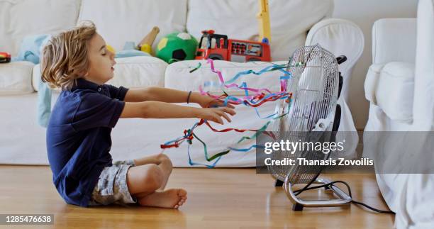 five year old boy standing in front of a fan and enjoy cool waves - refresh stock pictures, royalty-free photos & images