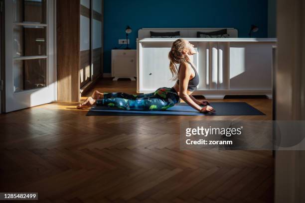 femme pratiquant le yoga à la maison - salutation au soleil photos et images de collection