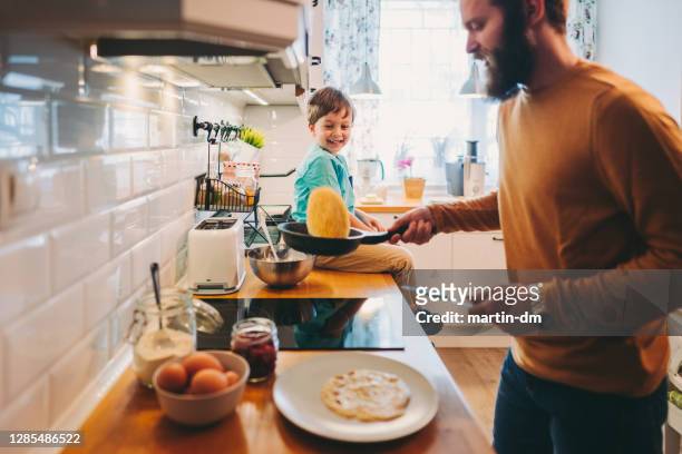 single father preparing pancakes during covid-19 lockdown - throwing stock pictures, royalty-free photos & images