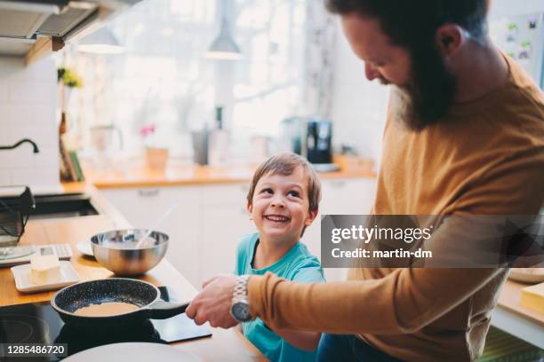 father and son making pancakes - leanincollection man stock pictures, royalty-free photos & images