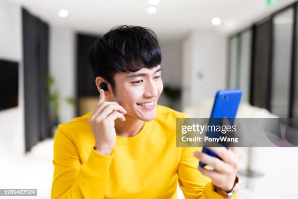asiatischer mann hat video-chat - in ear headphones stock-fotos und bilder