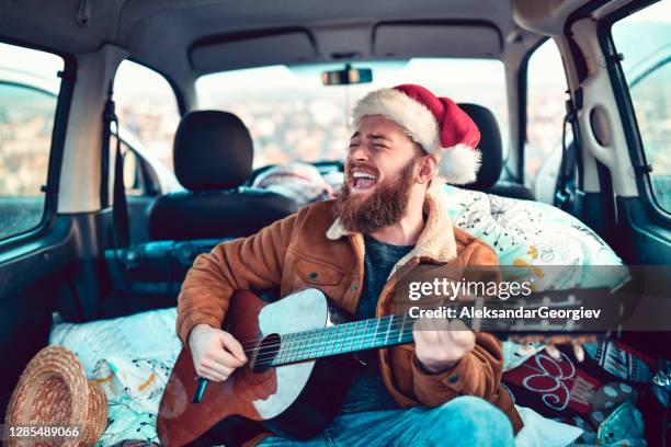 male enjoying christmas road trip with guitar in minivan - acoustic christmas stock pictures, royalty-free photos & images