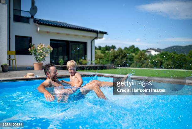 father with small son playing in swimming pool in backyard. - swimming pool photos et images de collection