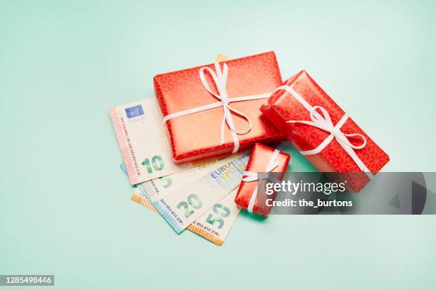 high angle view of wrapped christmas presents and euro banknotes on turquoise colored background, christmas bonus - christmas bonus stock pictures, royalty-free photos & images