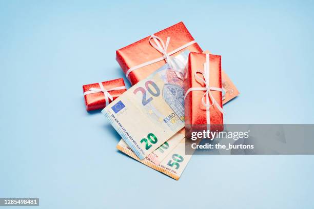 high angle view of wrapped christmas presents and euro banknotes on blue background, christmas bonus - geld stock-fotos und bilder