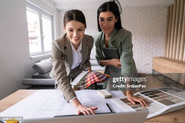 designer donne sorridenti che lavorano sulle idee d'interni e utilizzano un computer portatile - disegnatore dinterni foto e immagini stock