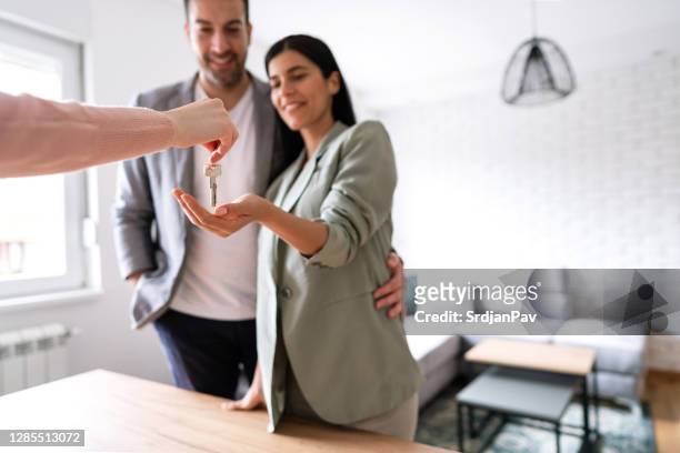 young couple receiving new apartment keys - handing over keys stock pictures, royalty-free photos & images
