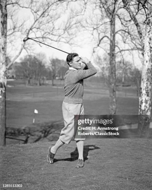 1930s Sports Man Golfer Wearing Sweater And Plus Fours Breeches Striking Hitting Golf Ball With Wooden Driver Club