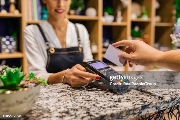 hand des kunden, der mit kontaktloser kreditkarte mit nfc-technologie bezahlt. - customers pay with contactless cards stock-fotos und bilder