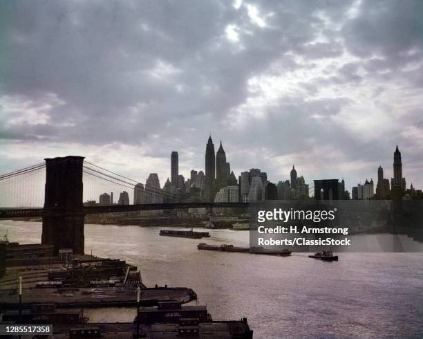 1950s Lower Manhattan Skyline With Brooklyn Bridge Tugs Barges Early Morning View Across East River New York City USA