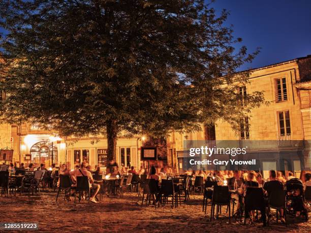 people dining outside in saint-emilion at dusk - bordeaux stock-fotos und bilder