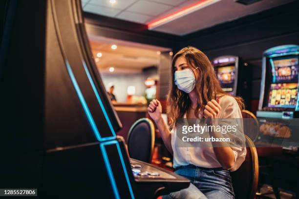 woman playing slot machine in casino - casino stock pictures, royalty-free photos & images