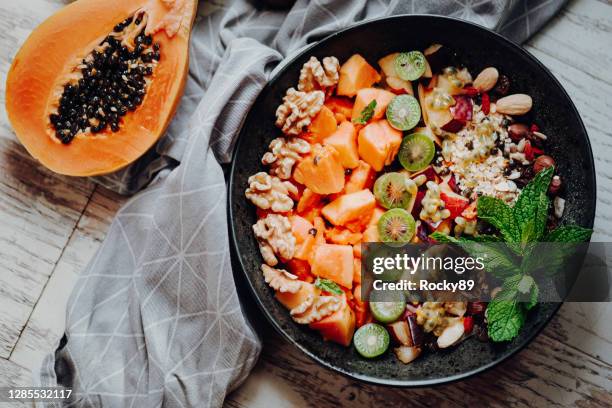 raw papaya smoothie bowl cubierto con kiwi, granola y nueces y nueces - dieta a base de plantas fotografías e imágenes de stock