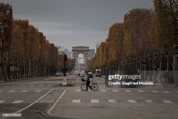 Cyclist crosses the Avenue des Champs-Élysées on November 13, 2020 in Paris, France. Nearly 4,900 Covid-19 patients are currently hospitalised in...