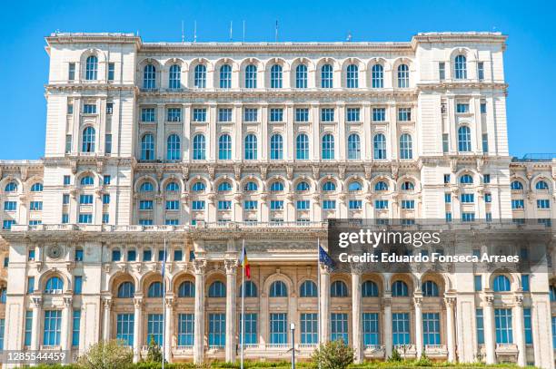 façade of the colossal romanian palace of parliament (palatul parlamentului) with flags - bucharest building stock pictures, royalty-free photos & images