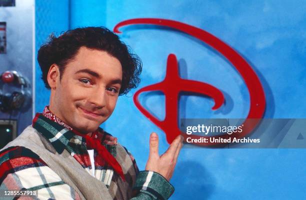 Moderator Thomas Tommy Krappweis mit dem Logo im Studio von Disney TV bei RTL in Köln, Deutschland 1994. .
