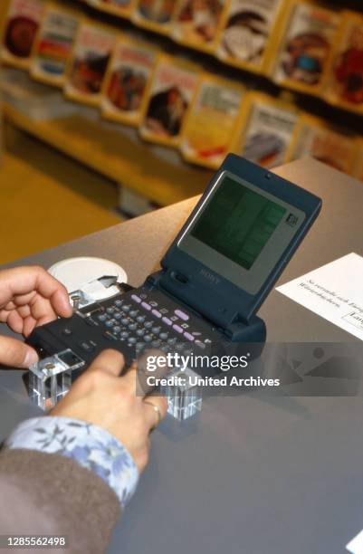 Eine junge Frau testet eine Handheld-Datenbank auf der Buchmesse in Frankfurt, Deutschland 1993.