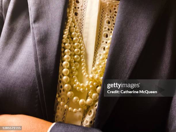 professional african-american woman dressed in smart navy work blazer & pearls with arms crossed - equal pay day stock pictures, royalty-free photos & images