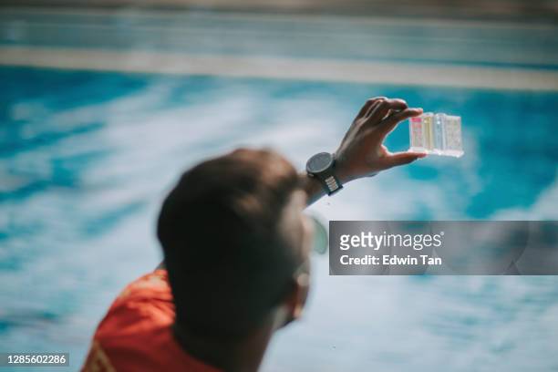 asian indian lifeguard pool testing kit being used in a swimming pool for water chlorine level - water testing stock pictures, royalty-free photos & images