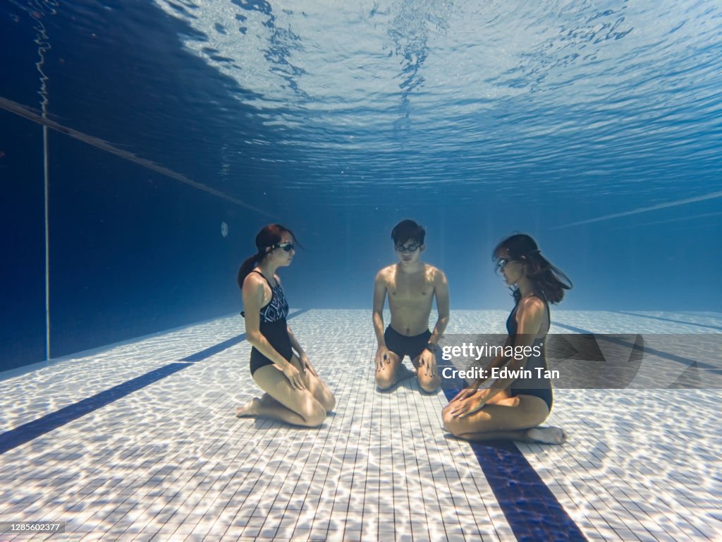 Asiatiska kinesiska tränare vägleda sin student undervattens andning övning i swimmingpool