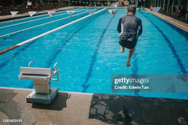 rear view asian chinese active senior man jump dive into the swimming pool - old people diving stock pictures, royalty-free photos & images