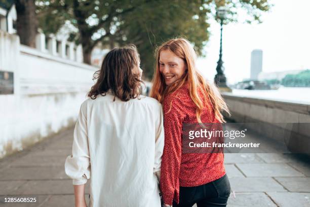 lesbisch paar dat gelukkig samen op de straat loopt - couple london stockfoto's en -beelden