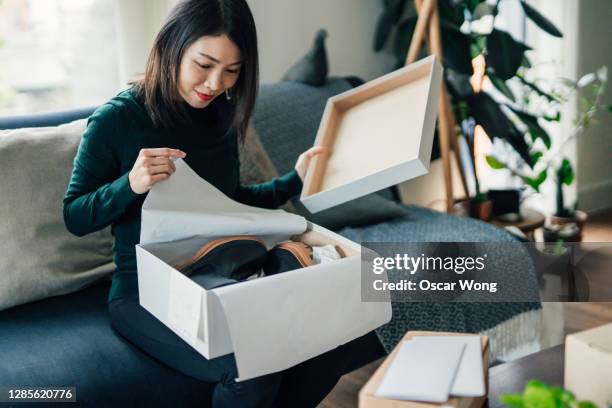 beautiful young woman unwrapping package at home - returning merchandise stock pictures, royalty-free photos & images