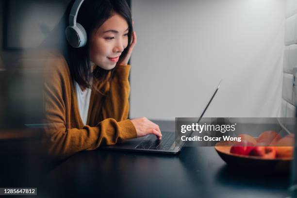 young beautiful woman studying online with laptop - asian watching movie stock pictures, royalty-free photos & images