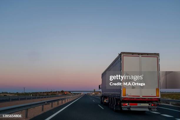 a truck travels down the highway at dusk - estrada nacional imagens e fotografias de stock