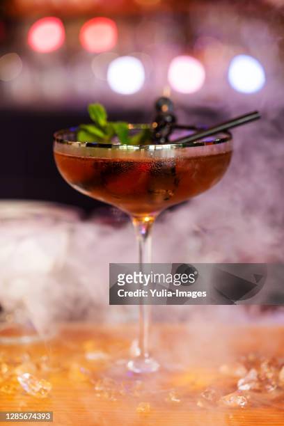 cocktail on a bar counter in a smoky atmosphere - cocktail counter stock-fotos und bilder