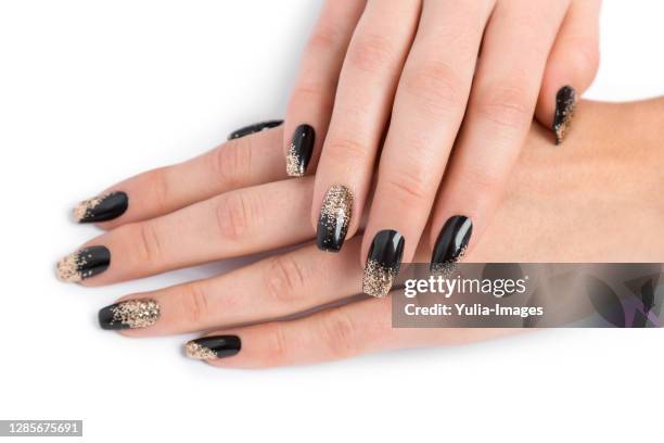 close up of stylish manicured hands painted black - gold nail polish stock-fotos und bilder