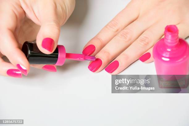 woman applying bright pink polish to nails - pink vanity stock pictures, royalty-free photos & images