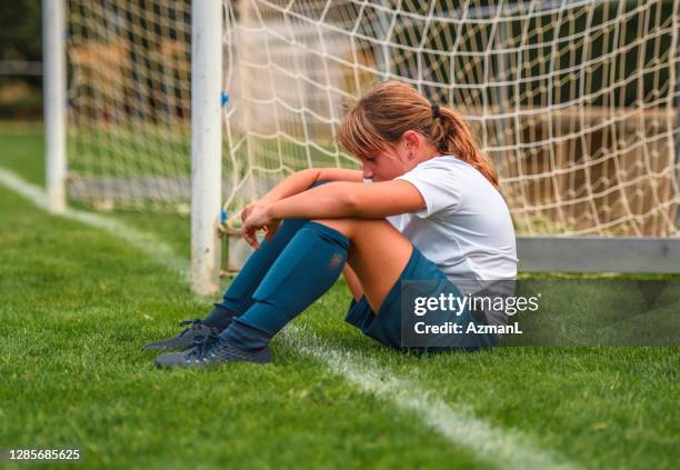 jonge zitting van de meisjevoetballer op gebied na praktijk - teleurstelling stockfoto's en -beelden